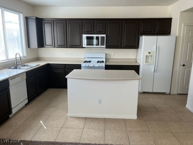 kitchen featuring light tile patterned flooring, sink, white appliances, and a kitchen island