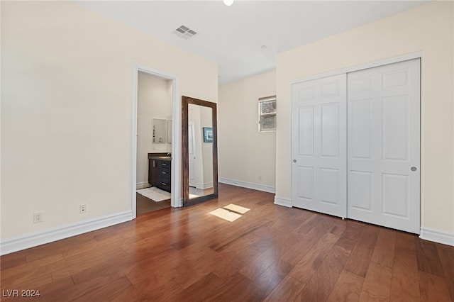 unfurnished bedroom with connected bathroom, a closet, and dark hardwood / wood-style floors