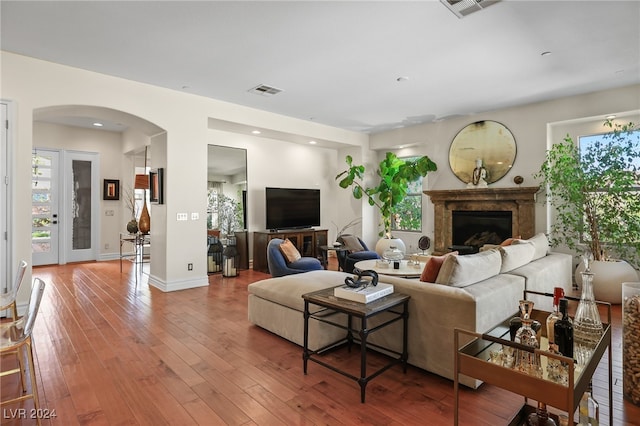 living room with plenty of natural light, hardwood / wood-style floors, and a high end fireplace