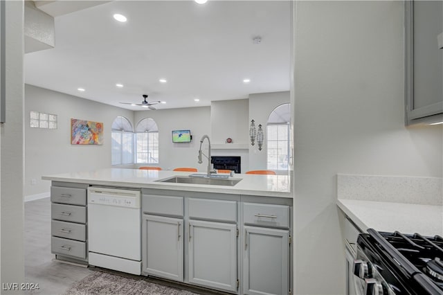 kitchen with gray cabinetry, white dishwasher, ceiling fan, stainless steel gas stove, and sink