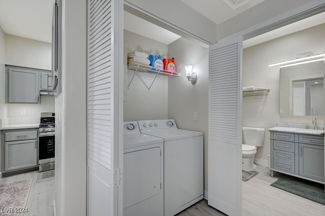 laundry area with sink, light hardwood / wood-style flooring, and independent washer and dryer