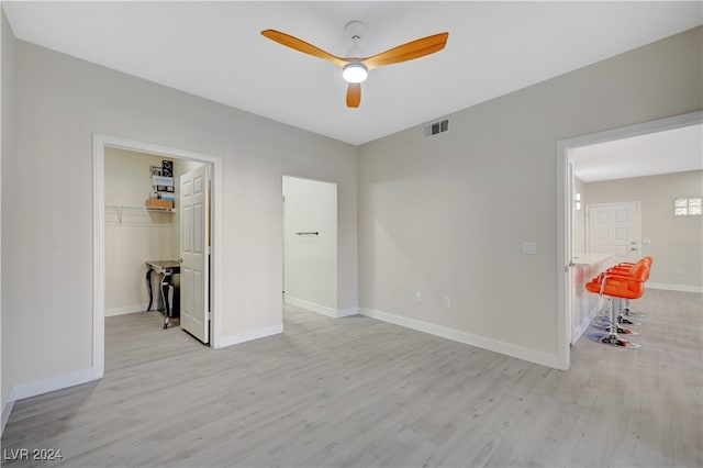 unfurnished bedroom featuring ceiling fan, a closet, light hardwood / wood-style floors, and a walk in closet