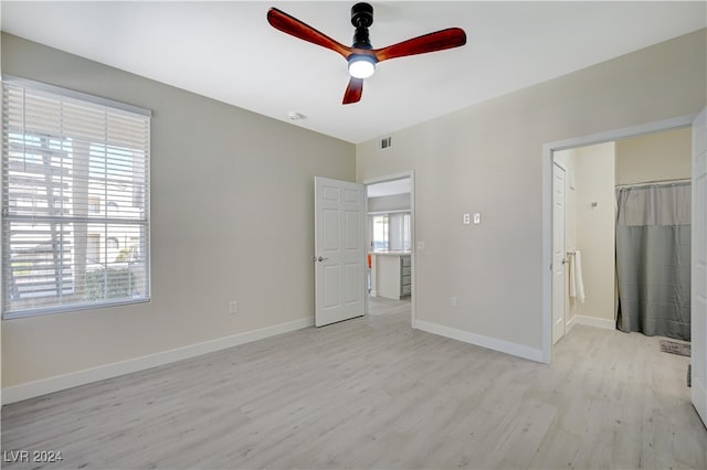 unfurnished bedroom featuring light hardwood / wood-style flooring, ceiling fan, and a walk in closet