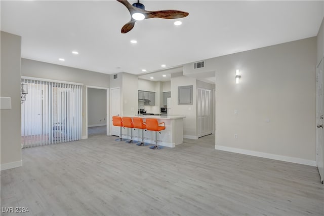 kitchen with kitchen peninsula, a kitchen bar, light hardwood / wood-style flooring, gray cabinetry, and ceiling fan