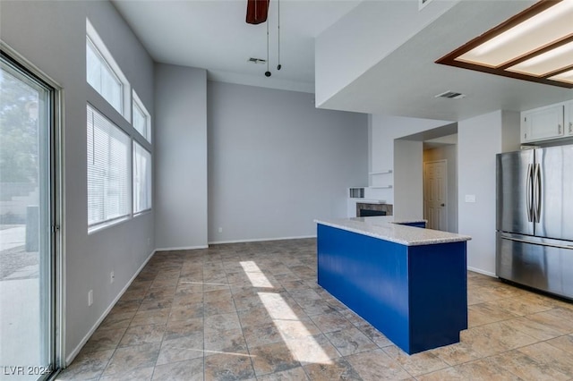 kitchen featuring ceiling fan, decorative light fixtures, stainless steel refrigerator, and white cabinetry