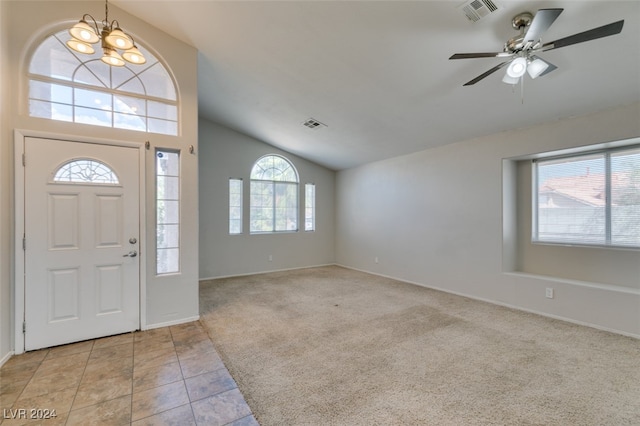 foyer entrance featuring ceiling fan with notable chandelier, lofted ceiling, and light colored carpet