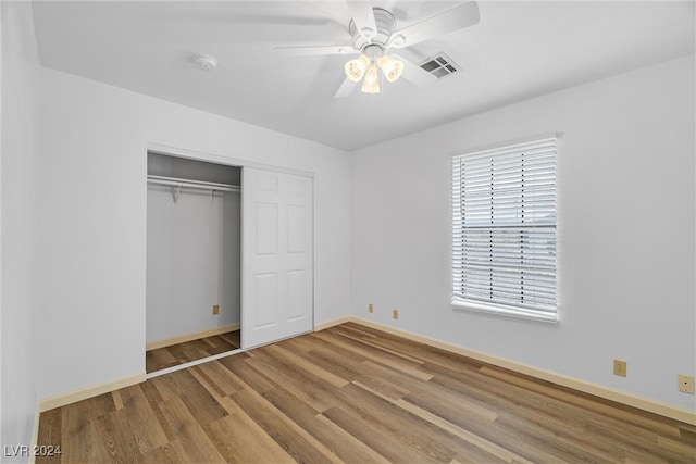 unfurnished bedroom with hardwood / wood-style flooring, ceiling fan, and a closet