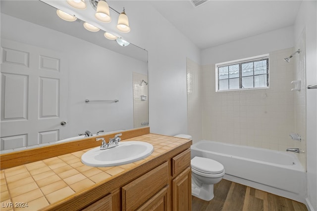 full bathroom with vanity, hardwood / wood-style flooring, toilet, and tiled shower / bath