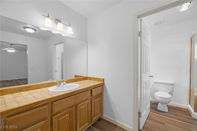 bathroom with wood-type flooring, vanity, toilet, and ceiling fan