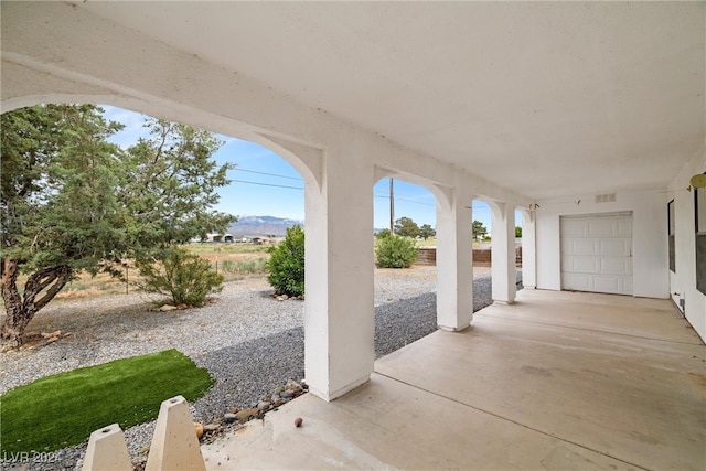 view of patio with a mountain view and a garage