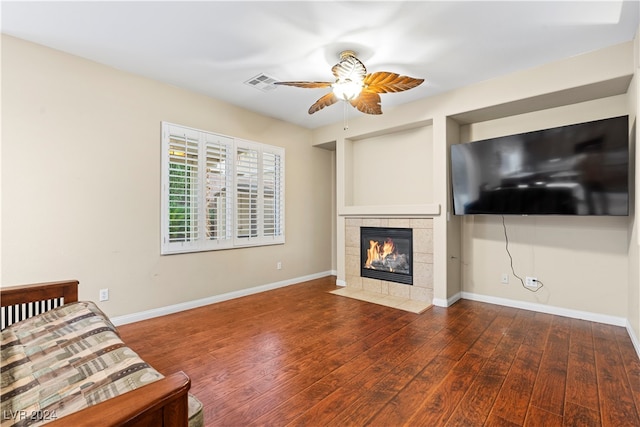 unfurnished living room with a fireplace, ceiling fan, and dark wood-type flooring