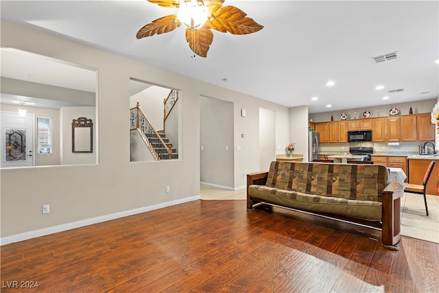 living room with dark hardwood / wood-style floors, ceiling fan, and sink