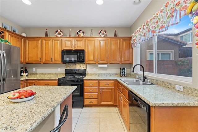 kitchen featuring light stone counters, sink, light tile patterned floors, and black appliances