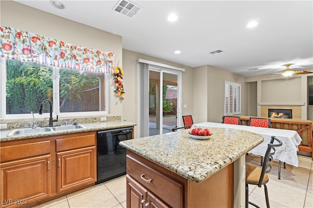 kitchen with sink, black dishwasher, light stone counters, a fireplace, and a kitchen island