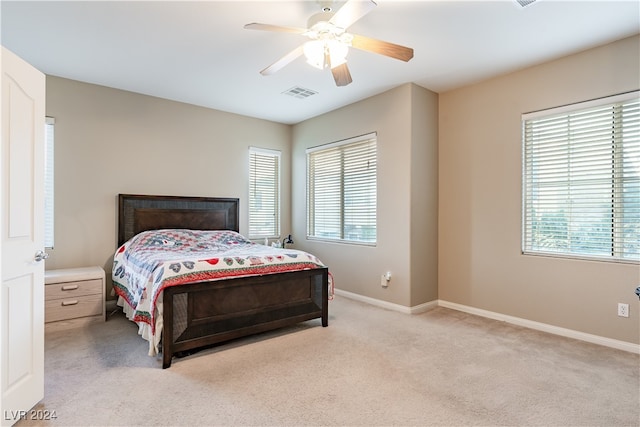 bedroom featuring ceiling fan, light carpet, and multiple windows