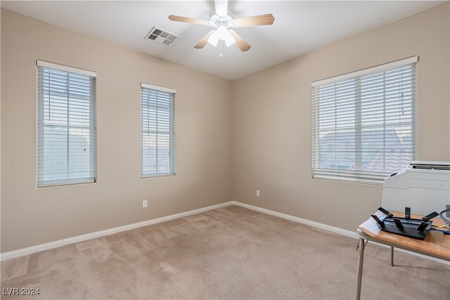 spare room featuring light colored carpet, a wealth of natural light, and ceiling fan