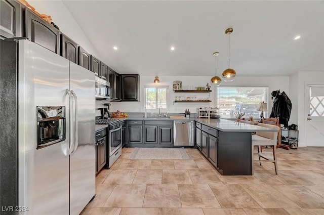 kitchen with a breakfast bar, hanging light fixtures, appliances with stainless steel finishes, a sink, and a peninsula