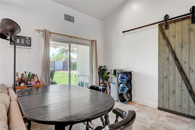 dining area featuring lofted ceiling, a barn door, visible vents, and baseboards