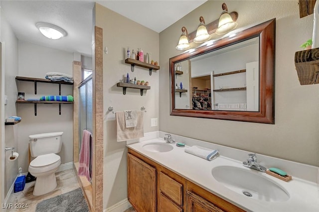 full bathroom featuring double vanity, a sink, toilet, and a shower stall