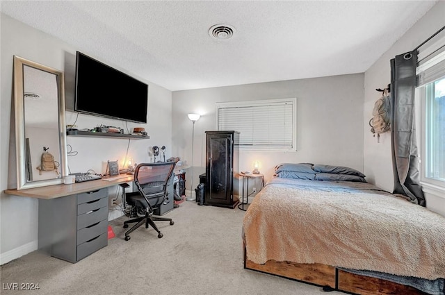 bedroom with a textured ceiling, baseboards, visible vents, and light colored carpet