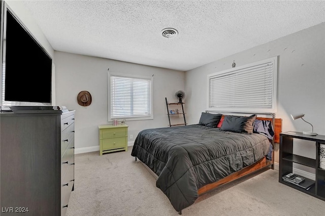 bedroom with light carpet, a textured ceiling, visible vents, and baseboards