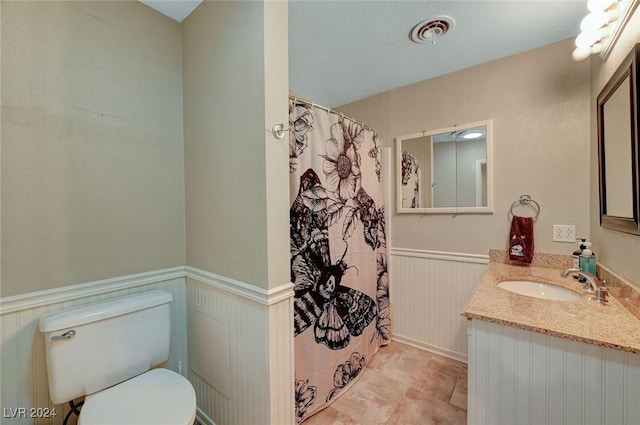 bathroom with visible vents, toilet, wainscoting, vanity, and a shower with curtain