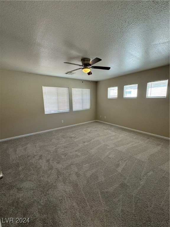 unfurnished room featuring a wealth of natural light, ceiling fan, and carpet floors