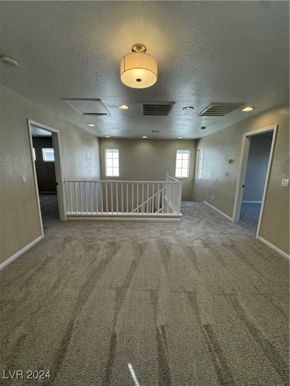 carpeted spare room featuring a textured ceiling