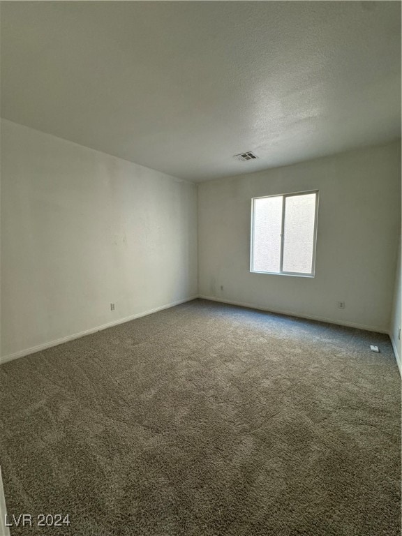 spare room with a textured ceiling and carpet