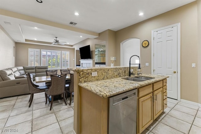 kitchen with light stone counters, sink, a center island with sink, ceiling fan, and stainless steel dishwasher