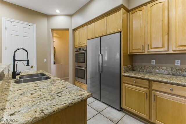 kitchen with light stone countertops, sink, appliances with stainless steel finishes, and light tile patterned floors