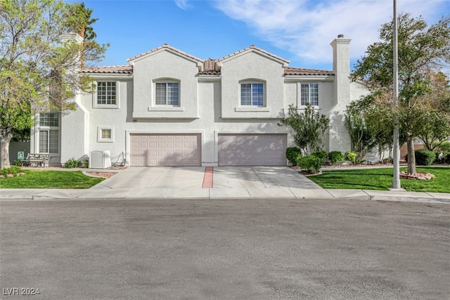 mediterranean / spanish home with a front yard, a garage, and central AC unit