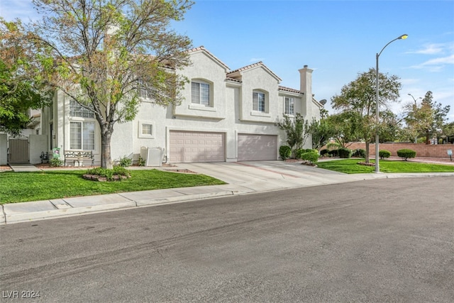 mediterranean / spanish-style home featuring a garage and a front lawn