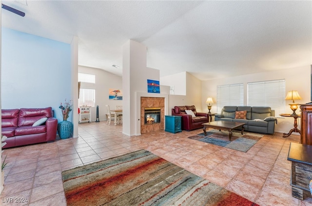 tiled living room with a textured ceiling, a tile fireplace, and lofted ceiling