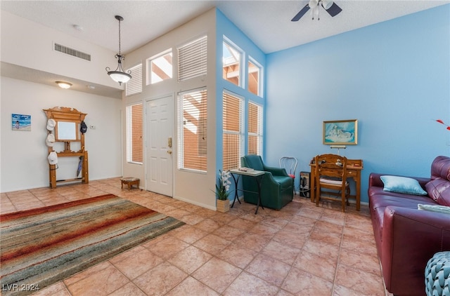 entryway with ceiling fan, light tile patterned flooring, and a high ceiling