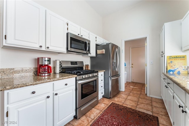 kitchen featuring stainless steel appliances, white cabinetry, and light stone counters