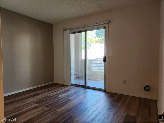 empty room with a textured ceiling and dark hardwood / wood-style floors