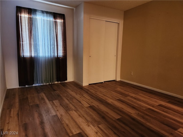 unfurnished bedroom with a closet and dark wood-type flooring