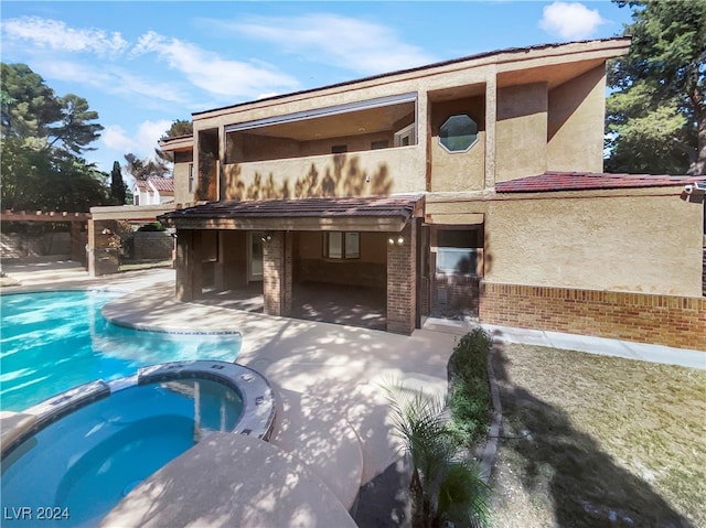 back of house with a patio area and a pool with hot tub