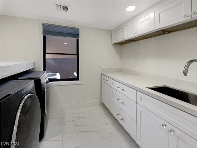 laundry room with cabinets, washer and dryer, and sink