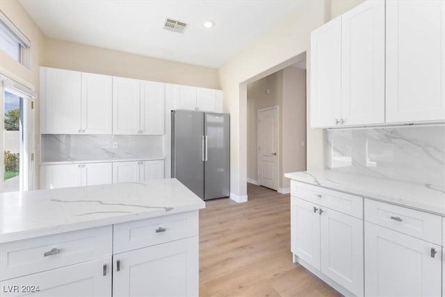 kitchen featuring baseboards, white cabinetry, freestanding refrigerator, and backsplash