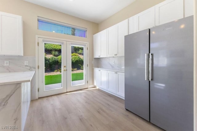 kitchen featuring tasteful backsplash, french doors, freestanding refrigerator, and white cabinetry