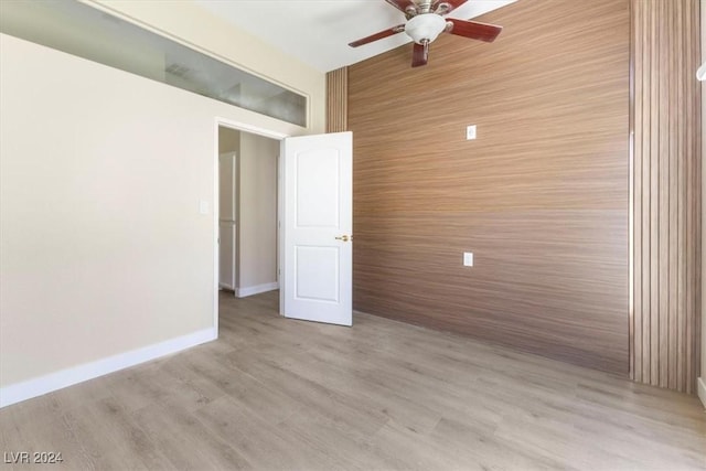 empty room featuring light wood-style flooring, baseboards, and a ceiling fan