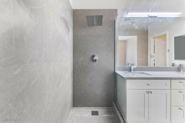 bathroom featuring double vanity, a tile shower, and a sink