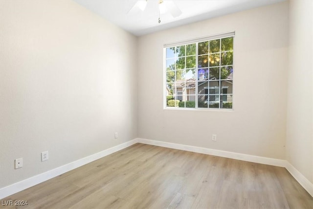 spare room featuring baseboards, light wood finished floors, and ceiling fan