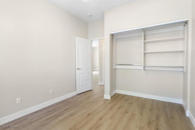 unfurnished bedroom featuring a closet, baseboards, and wood finished floors
