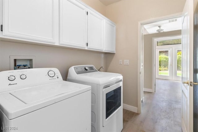 washroom featuring light wood-type flooring, baseboards, washing machine and dryer, visible vents, and cabinet space
