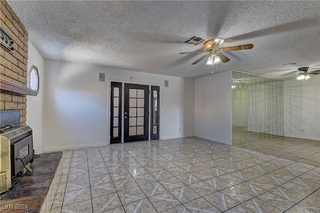 unfurnished living room with a textured ceiling, ceiling fan, and a wood stove