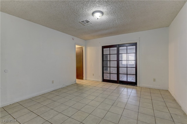 spare room featuring a textured ceiling and light tile patterned floors