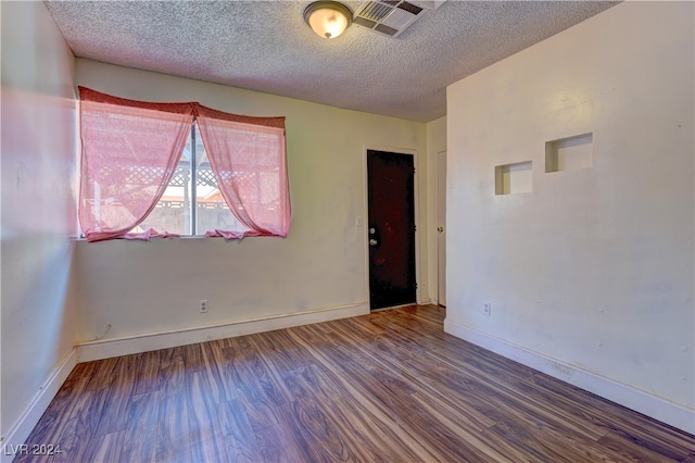 spare room with a textured ceiling and dark hardwood / wood-style floors